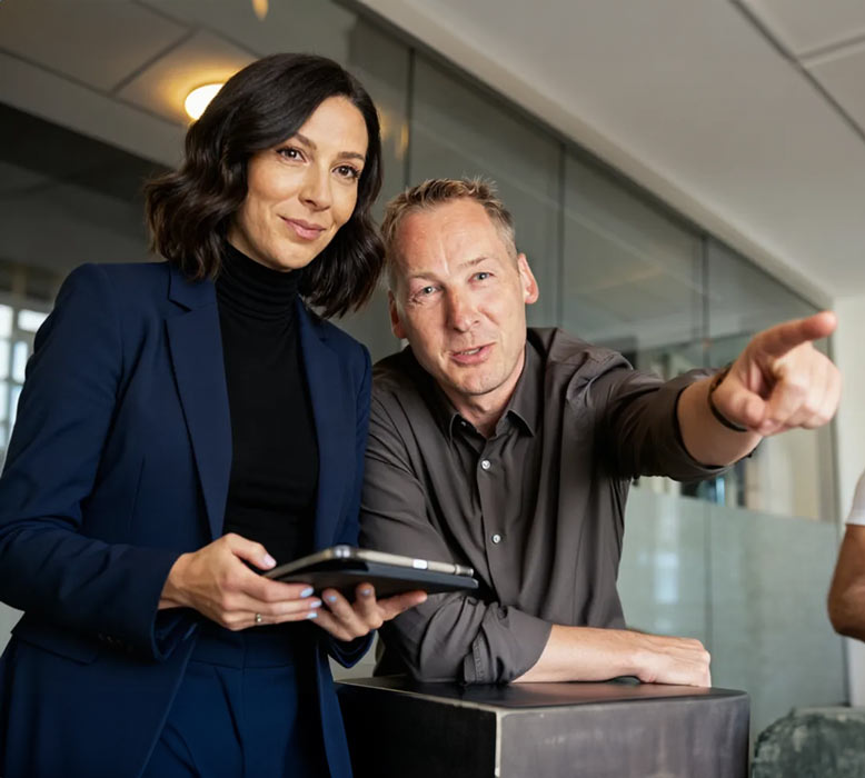 Werbeagentur und Onlinemarketing Agenturchef erklärt einer Frau, die ein Tablet in der Hand hält, die Ergebnisse der Werbe und Druck Kampagne.